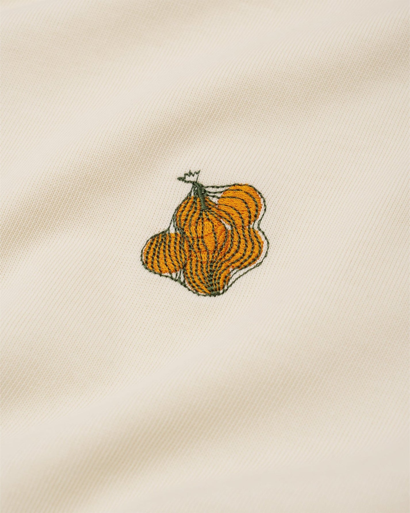 Embroidered design of a cluster of oranges on a cream fabric t-shirt